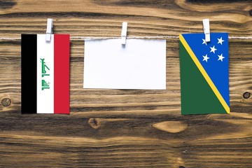 Hanging flags of Iraq and Solomon Islands attached to rope with clothes pins with copy space on...