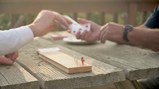 Old Friends Play Cribbage on old wooden table