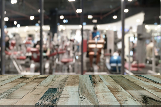 Wooden table with blur fitness gym equipment background