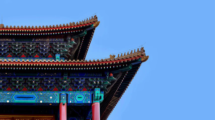 Fototapeta premium curved roofs in traditional Chinese style with figures on the blue sky background. The Imperial Palace in Beijing