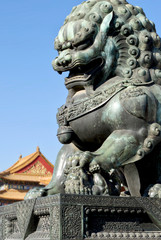 bronze lions on the background of the buildings of the imperial palace. The Imperial Palace in Beijing