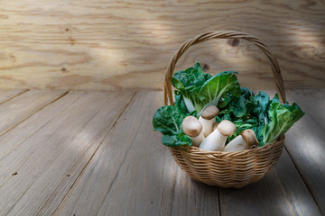 Fototapeta na wymiar king oyster mushrooms and pak choi in wicker basket on wooden table