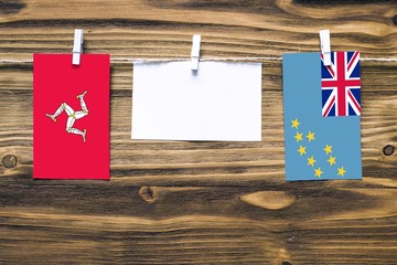 Hanging flags of Isle Of Man and Tuvalu attached to rope with clothes pins with copy space on white...