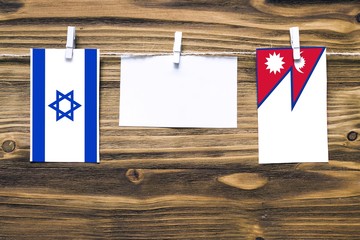 Hanging flags of Israel and Nepal attached to rope with clothes pins with copy space on white note...