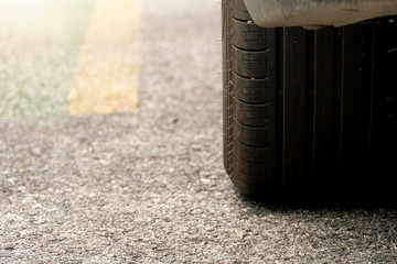 Close up beside tire of car on asphalt road. Rubber patterns with stones have been used on the road.