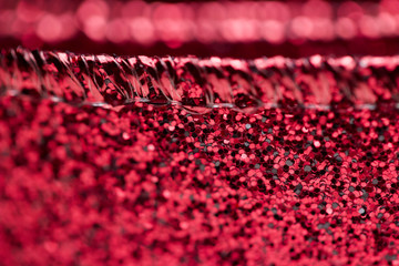 Macro abstract texture view of glittering defocused red fabric ribbon with bokeh