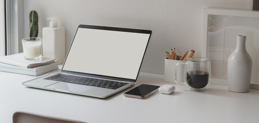 Minimal workspace with open blank screen laptop computer and office supplies