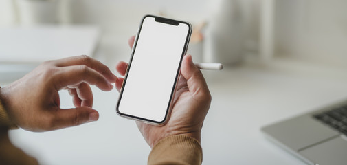 Cropped shot of young male freelancer looking at blank screen smartphone