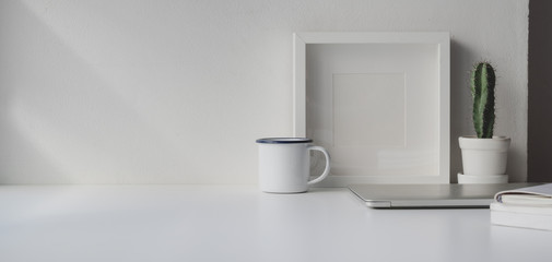 Obraz na płótnie Canvas Minimal workspace with copy space and mock up frame on white wooden table and white wall