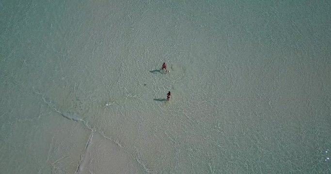 Young lovers playing in the quite and clear ocean waves that brings simple yet natural beauty of thy nature in Canada - Aerial Shot