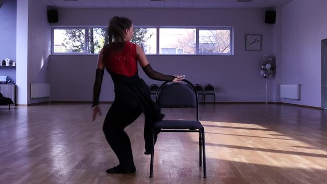 Professional female dancer dances around two chairs