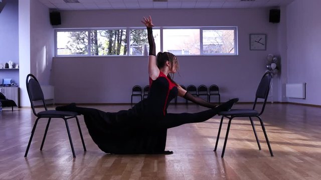 Professional female dancer does a split on two chairs