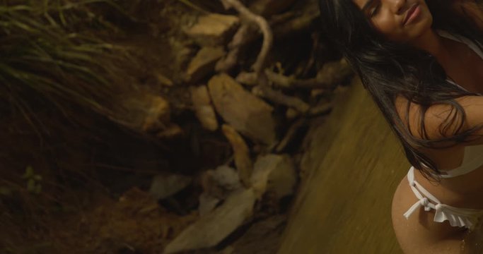 A young girl in the water with a scenic background while the camera does a 360 roll on a gimbal