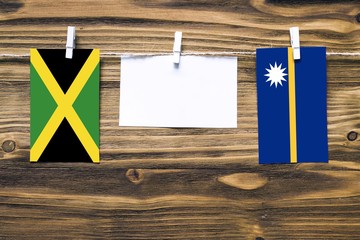 Hanging flags of Jamaica and Nauru attached to rope with clothes pins with copy space on white note paper on wooden background.Diplomatic relations between countries.