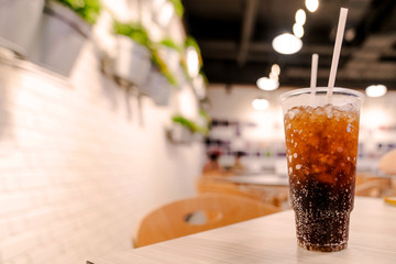 cola water and ice in plastic cup with restaurant background