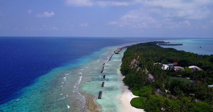 round tropical island resort hotel with white sand palm trees and turquoise Indian ocean on Maldives