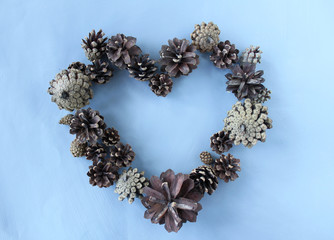 Heart made of pine cones on blue background