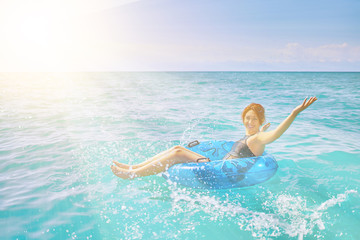 Amazing young woman relax on inflatable ring make water splash in sea water
