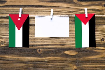 Hanging flags of Jordan and Palestine attached to rope with clothes pins with copy space on white...
