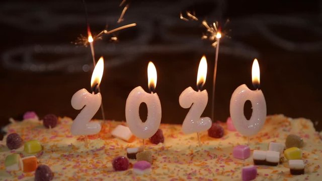 New Year 2020 burning candles on celebration cake