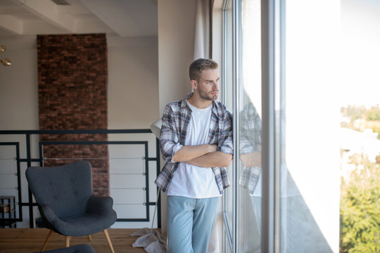 Man standing near window and enjoying the view - Powered by Adobe
