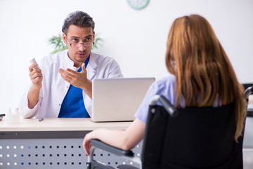 Young woman in wheel-chair visiting male doctor