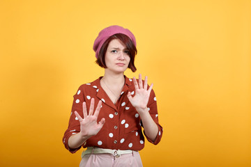 Beautiful young woman wearing red shirt in white polka dot over isolated background, displeased and fearful doing disgust face because aversion reaction. With hands raised. Annoying concept.