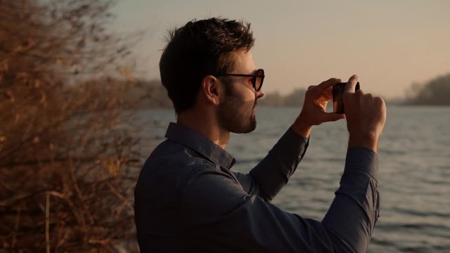 Mobile Photo.Picture On Smartphone.Man Taking Mobile Photo.Man Holding Mobile Phone Taking Picture At Sunset.Close Up Attractive Male Happy Using Mobile App For Photo Or Video.