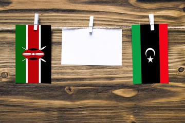 Hanging flags of Kenya and Libya attached to rope with clothes pins with copy space on white note...