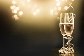 two champagne glasses with ribbons against holiday lights and fireworks - New Year celebrations