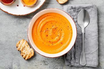 Pumpkin and carrot soup with spices on  on grey stone background. Top view.