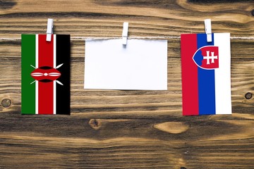 Hanging flags of Kenya and Slovakia attached to rope with clothes pins with copy space on white...