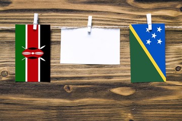 Hanging flags of Kenya and Solomon Islands attached to rope with clothes pins with copy space on...