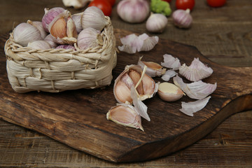organic garlic in a basket and garlic on a wooden rustic board on the background of vegetables. Health concept.