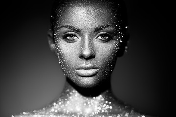 Fashion model woman in bright sparkles and lights posing in studio. Portrait of beautiful sexy woman. Art design glitter glowing make up. Black and white photography - obrazy, fototapety, plakaty