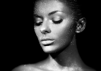 Fashion model woman in bright sparkles and lights posing in studio. Portrait of beautiful sexy woman. Art design glitter glowing make up. Black and white photography