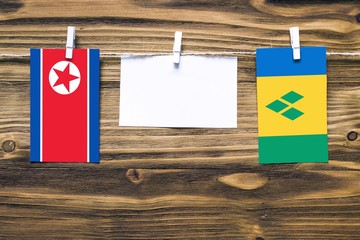 Hanging flags of North Korea and Saint Vincent And The Grenadines attached to rope with clothes...