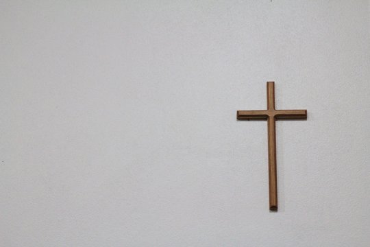 a wooden cross on the white wall background
