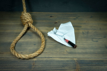 Rope noose around crumpled paper and pencil