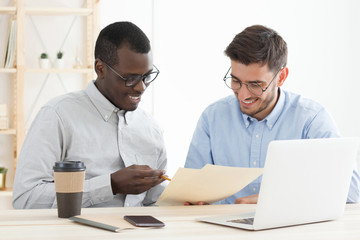 Diversity in education. African male teacher supporting his caucasian adult student while he is doing task