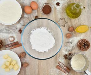 Tools and products for baking homemade gingerbread cookies on a wooden background. The concept of the holiday, celebration and cooking. Eggs, butter, flour, cocoa, nuts, vanillin, anise, cones.