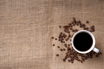 cup of coffee and coffee beans on jute