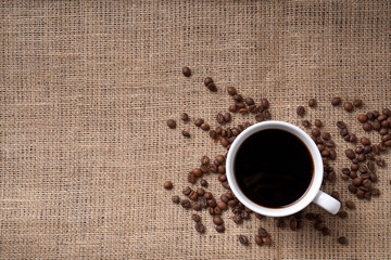 cup of coffee and coffee beans on jute