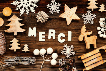 Letters Building The Word Merci Means Thank You. Wooden Christmas Decoration Like Tree, Sled And Star. Brown Wooden Background