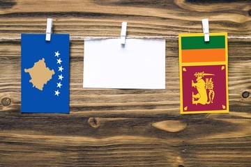 Hanging flags of Kosovo and Sri Lanka attached to rope with clothes pins with copy space on white note paper on wooden background.Diplomatic relations between countries.