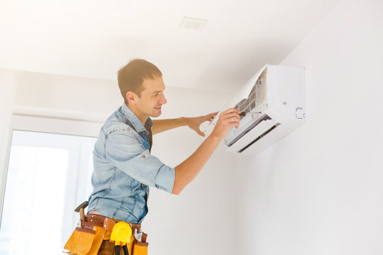man repair air conditioner - a man is working on a ceiling air conditioner