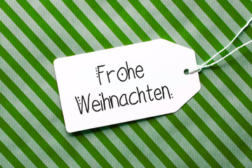 Label With German Calligraphy Frohe Weihnachten Means Merry Christmas. Green Wrapping Paper As Background