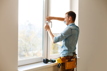 Naklejka na ściany i meble Man worker mounting window on balcony.