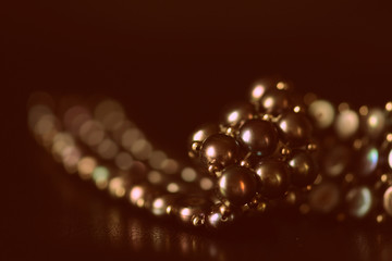 Black pearl necklace on a dark background close up. Retro style toned