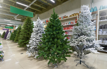 Sale of many artificial Christmas trees in green, purple and white at a decor store. The sale of a variety of artificial Christmas trees